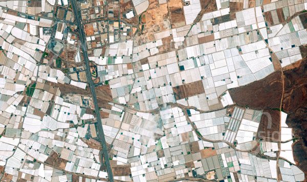Das Satellitenbild "EL EJIDO - Spanien" ist dem Bildband "HUMAN FOOTPRINT - Satellitenbilder dokumentieren menschliches Handeln" entnommen. Bildbeschreibung: Unterirdische Wasservorräte und das Was­ser aus den Ausläufern der Sierra Nevada ermöglichen in der unfruchtbaren Wüste um El Ejido in Südspanien die Bewirtschaftung der weltweit größten Anbaufläche unter Folie. Zu der durch Wasserverbrauch und Pestizideinsatz im mehr als 360 Quadratkilometer umfassenden „mar del plástico“ (Plastikmeer) bedenklichen ökologischen Situation gesellen sich soziale Probleme schlecht bezahlter Arbeitskräfte.