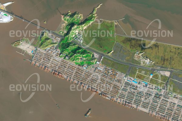 Das Satellitenbild "YANGSHAN PORT - China" ist dem Bildband "NEW HUMAN FOOTPRINT - Unsere Welt im Umbruch" entnommen. Bildbeschreibung: Da der am Ufer des Jangtse gelegene Hafen Shanghais wegen seiner Gezeitenabhän­gigkeit die steigenden Gütermengen nicht mehr bewältigte, wurde 25 Kilometer vor der Küste ein neuer Tiefseehafen errichtet. Auf künstlich erweiterten Inseln entstand in der Hangzhou-Bucht ein Containerhafen mit dem weltweit größten automatisierten Terminal, an dem 2015 mehr als 36 Millionen Standardcontainer umgeschlagen wurden. Der Vollausbau des Hafens ist für 2020 ge­plant. Der Hafen ist über die Donghai-Brücke erreichbar, mit 32,5 Kilometern Länge die längste Meeresbrücke der Welt.