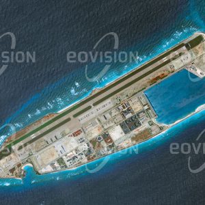 Das Satellitenbild "FIERY CROSS REEF 31May2014 - " ist dem Bildband "NEW HUMAN FOOTPRINT - Unsere Welt im Umbruch" entnommen. Bildbeschreibung: Die beiden Satellitenbilder vom 31. Mai 2014 (oben) und vom 14. Juni 2018 (unten) verdeutlichen, welchen Aufwand Staaten zu treiben gewillt sind, um ihre Interessen zu wahren. Innerhalb weniger Jahre wurde bei den Spratly-Inseln im Südchinesischen Meer ein Korallenriff in eine Insel umgewandelt, auf der eine kleine Stadt samt Sportanlagen mit Fußballplatz und Tennisplätzen errichtet wurde. Sie beherbergt eine Militärgarnison, die über einen eigenen Flughafen mit einem 3,3 km langen Landestreifen verfügt.