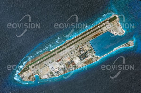 Das Satellitenbild "FIERY CROSS REEF 31May2014 - " ist dem Bildband "NEW HUMAN FOOTPRINT - Unsere Welt im Umbruch" entnommen. Bildbeschreibung: Die beiden Satellitenbilder vom 31. Mai 2014 (oben) und vom 14. Juni 2018 (unten) verdeutlichen, welchen Aufwand Staaten zu treiben gewillt sind, um ihre Interessen zu wahren. Innerhalb weniger Jahre wurde bei den Spratly-Inseln im Südchinesischen Meer ein Korallenriff in eine Insel umgewandelt, auf der eine kleine Stadt samt Sportanlagen mit Fußballplatz und Tennisplätzen errichtet wurde. Sie beherbergt eine Militärgarnison, die über einen eigenen Flughafen mit einem 3,3 km langen Landestreifen verfügt.