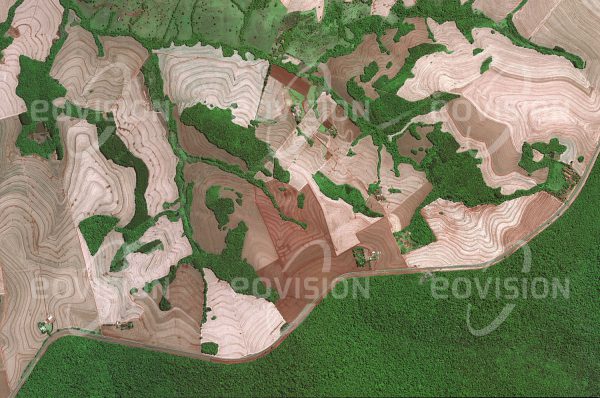 Das Satellitenbild "IGUAZU NATIONALPARK - Brasilien - Argentinien" ist dem Bildband "NEW HUMAN FOOTPRINT - Unsere Welt im Umbruch" entnommen. Bildbeschreibung: Der Gegensatz zwischen Natur- und Kultur­landschaft erscheint oft an der Grenze eines Naturschutzgebietes am deutlichsten. Der Rand des Nationalparks Iguazu, der vor allem für seine Wasserfälle bekannt ist, bildet eine scharfe Grenze, an die sich eine landwirt­schaftliche Fläche mit geringen Waldresten anschließt. Gut zu erkennen ist, wie zur Vermeidung von Bodenerosion die Felder durch Konturpflügen quer zur Hangneigung bewirtschaftet werden. Nur 30 Kilometer entfernt liegt der Itaipu-Staudamm, dessen Kraftwerk mit einer Turbinenleistung von 14 Gigawatt eines der weltweit größten ist.