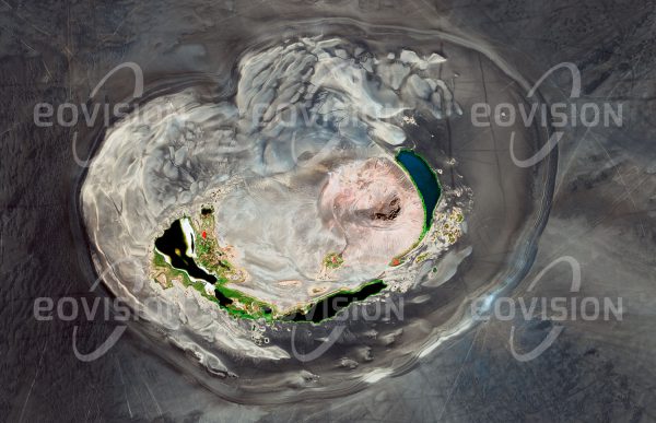 Das Satellitenbild "WAW AN-NAMUS - Libyen" ist dem Bildband "WÜSTEN - Lebensraum der Extreme" entnommen. Bildbeschreibung: Waw an-Namus ist ein erloschener Vulkan im Süden Libyens. Alter und Ursprung des Vulkanismus in dieser Region im Herzen der Sahara sind nicht sicher bekannt. Die helle Caldera mit mehr als vier Kilometer Durchmesser ist umgeben von dunklem Eruptionsmaterial (Tephra). Innerhalb der Caldera befindet sich ein Vulkankegel aus hellem Auswurfgestein. Waw an-Namus bedeutet Moskito-Oase, weil um die Seen am Grund der Caldera zahlreiche Mücken leben. Die Seen erscheinen in unterschiedlichen Farben, die vom Salz- und Algengehalt des Wassers abhängen.