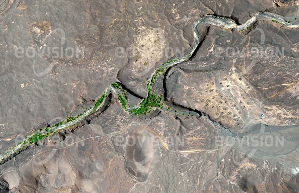 Das Satellitenbild "YEBBI SOUMA - Tschad" ist dem Bildband "WÜSTEN - Lebensraum der Extreme" entnommen. Bildbeschreibung: In der Oase Yebbi Souma liegt eine Siedlung des Volks der Tubu. Hier tritt an den nördlichen Ausläufern des Tibesti Grundwasser aus und sorgt für eine ganzjährige Verfügbarkeit von Wasser. In der Schlucht finden sich Palmen und bewässerte Felder, während die schilfgedeckten Rundbauten des Dorfs auf dem anschließenden Plateau stehen. Das Gebiet gehört zum Aouzou-Streifen, der bis in die 1990er Jahre zwischen Libyen und dem Tschad heftig umstritten war.