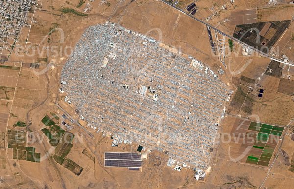 Das Satellitenbild "AZ-ZAATARI - Jordanien" ist dem Bildband "WÜSTEN - Lebensraum der Extreme" entnommen. Bildbeschreibung: Kriegerische Konflikte sind der häufigste Grund, dass Menschen ihre Heimat verlassen. Wie die Konflikte selbst sind daher auch Flüchtlingslager kein neues Phänomen. Das für maximal 80.000 Bewohner geplante Az-Zaatari im Norden Jordaniens gehört zu den größten Flüchtlingslagern der Welt. Es entstand 2012 als Folge des syrischen Bürgerkriegs, durch den bis 2015 fast 12 Millionen Menschen vertrieben wurden. Im März 2013 beherbergte das Lager sogar mehr als 156.000 Menschen. Unter der Leitung des UNHCR (Flüchtlingswerk der Vereinten Nationen) hat sich Az-Zataari zu einer eigenen Stadt entwickelt.